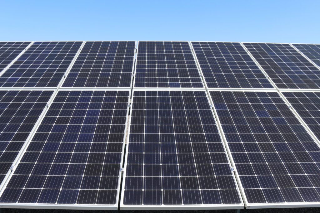 Professional solar panel cleaning services - AustClean roof and solar panel maintenance team cleaning blue solar panels on Australian residential roof under clear blue sky for optimal energy efficiency